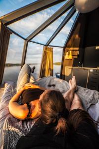 une femme qui se couche sur un lit sur un bateau dans l'établissement Vikajärvi Lake View Experience Igloos, à Rovaniemi