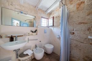een badkamer met een wastafel, een toilet en een spiegel bij La Lamia 1864 by Rentbeat in Ostuni