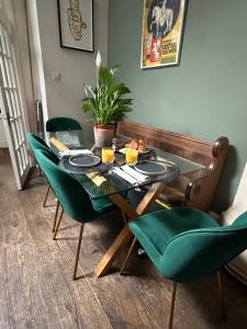 una mesa de comedor con sillas verdes y una mesa con comida. en Converted church, en Beckenham