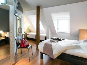 una camera con un letto e una sedia e una finestra di ibis Colmar Centre a Colmar