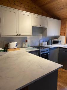 cocina con armarios blancos y encimera en Cozy Cabin with Stunning Loch Lomond Views en Rowardennan