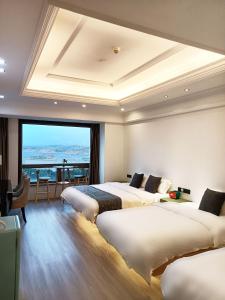 ein Hotelzimmer mit 3 Betten und einem großen Fenster in der Unterkunft PingTan YuCheng Seaview Blue Smart Hotel in Pingtan