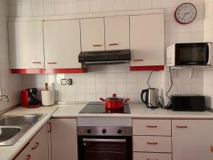 a kitchen with white cabinets and a red pot on the stove at Sagunto in Sagunto