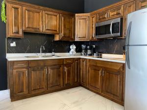a kitchen with wooden cabinets and a white refrigerator at Ancla Suite 8 - 2 Bedroom Urban Hotel in Puerto Peñasco