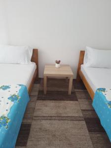 Cette chambre comprend 2 lits et une table. dans l'établissement Centar Apartment, à Gevgelija