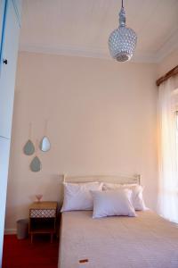 a bedroom with a bed with white sheets and a chandelier at The Art House By The Sea in Plomarion