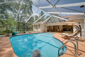 a swimming pool with an umbrella and chairs next to a house at 4 Mi to Rainbow Springs Dunnellon Villa with Pool! in Dunnellon