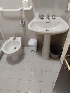 uma casa de banho branca com um lavatório e um WC em IL RISVEGLIO em Sella Nevea