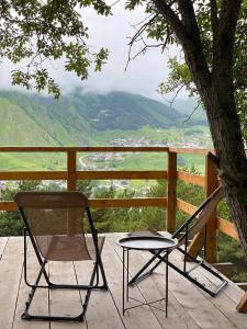 two chairs and a table on a porch with a tree at Elia Glamping in Stepantsminda