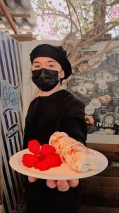 a person wearing a mask holding a plate of food at Leão Beach Pousada in Luis Correia