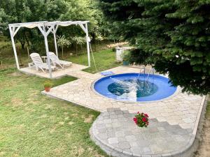 a small pool with a table and chairs in a yard at Apartman White House with sauna ,pool and jacuzzi in Novi Sad