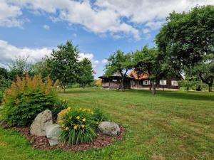 a yard with a house and some flowers and rocks at Anykščiai MĖNULIO AKMUO in Stariai