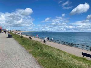 a group of people walking on a sidewalk next to the beach at Spacious Ground Floor 2 Bed by Lains Lettings in Aberdeen