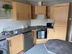 a kitchen with wooden cabinets and a sink and a stove at Spacious Ground Floor 2 Bed by Lains Lettings in Aberdeen