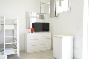 a white room with a tv on a dresser at RESORT LEONARDO- Room, Pool & Restaurant in San Foca