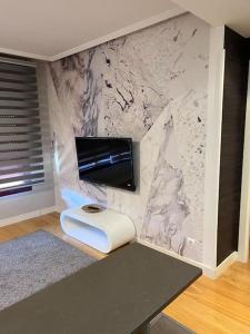 Relájate después de patear Madrid في مدريد: غرفة بها جدار من الرخام مع طاولة وتلفزيون