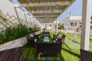 a row of chairs and tables under a pergola at RESORT LEONARDO- Room, Pool & Restaurant in San Foca