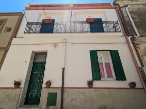 a white building with green shutters and a balcony at Casa Ficumora in Modica