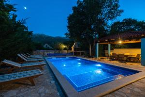 una piscina en un patio trasero con sillas y mesa en Villa Lino, en Dugopolje