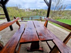 a wooden picnic table sitting on top of a porch at Pixie House - Mrežnica, private pier, hot tub in Gornji Zvečaj