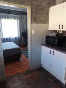 een kamer met een bed en een keuken met een magnetron bij The Private and Cosy Guest House 1 in Germiston