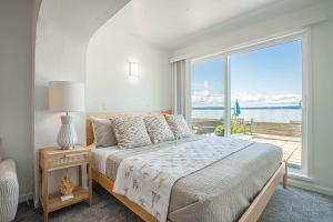 a white bedroom with a bed and a large window at Waterfront Bliss, 2 BR Apt near Alki Beach in Seattle