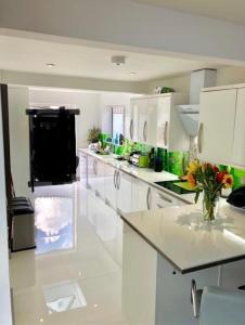 une cuisine avec des comptoirs blancs et un vase de fleurs dans l'établissement Pevensey Bay Villa, à Pevensey