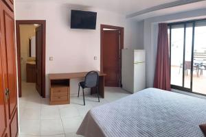 ein Hotelzimmer mit einem Bett, einem Schreibtisch und einem Fenster in der Unterkunft Apartamento Castillo - Alquiler de temporada in Puerto de Sagunto