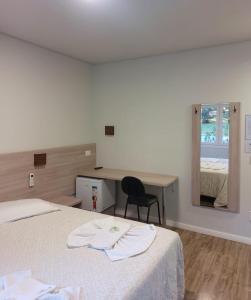 1 dormitorio con cama, escritorio y espejo en Filadélfia Hospedagens e Eventos, en São Bento do Sul
