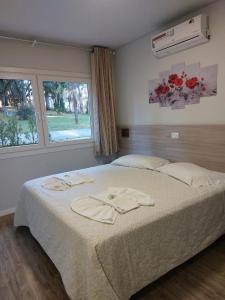 a bedroom with a bed with white sheets and a window at Filadélfia Hospedagens e Eventos in São Bento do Sul