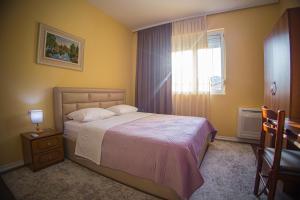 - une chambre avec un lit, une fenêtre et une chaise dans l'établissement Vila Visi Hotel, à Korçë