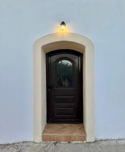 a black door in a white wall with a light on top at The Old barrel houses in Kythira