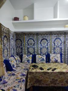 Cama en habitación con papel pintado azul y blanco en Casa Fahssi, en Chefchaouen