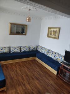 sala de estar con sofá azul y TV en Casa Fahssi, en Chefchaouen