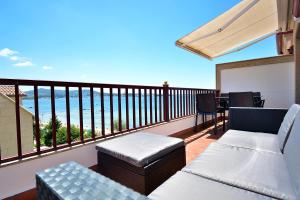 a balcony with two couches and a table and chairs at Ático con terraza y vistas al mar en Vilagarcía in Vilagarcia de Arousa