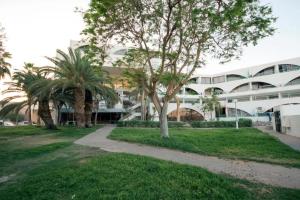 a large white building with palm trees in front of it at Milano Suite in Lev Eilat in Eilat