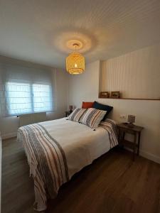 um quarto com uma cama grande e um lustre em Ático en Llanes con terraza junto Paseo San Pedro em Llanes