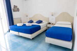 2 letti in una camera con blu e bianco di Hotel La Luna a Ischia