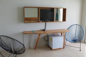 a desk with a television and two blue chairs at Rocamar Hotel Isla Mujeres in Isla Mujeres