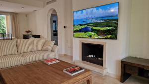 een woonkamer met een tv boven een open haard bij Golf and Beach Marbella (4+1Pax-2.5Bath) in Marbella