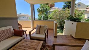een patio met een bank en stoelen op een balkon bij Golf and Beach Marbella (4+1Pax-2.5Bath) in Marbella