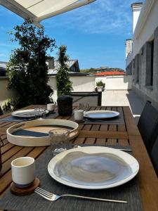 uma mesa de madeira com pratos e utensílios num pátio em Ático en Llanes con terraza junto Paseo San Pedro em Llanes