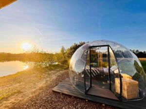 a glass dome tent sitting on a wooden deck next to a lake at Beheiztes Bubble Tent am See - Sternenhimmel in Wadersloh