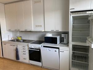 eine Küche mit weißen Schränken, einer Spüle und einer Mikrowelle in der Unterkunft kauppalankatu kolmio in Kouvola