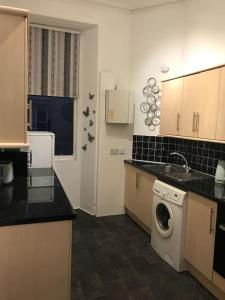 uma cozinha com um lavatório e uma máquina de lavar roupa em Grange Lone entire apartment with two double beds em Edimburgo