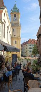 un grupo de personas sentadas en sillas frente a una torre del reloj en nice flat under the castle, en Bratislava