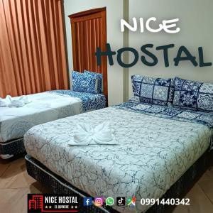 dwa łóżka w pokoju ze szpitalnym znakiem Nike w obiekcie Nice Hostal El Quinche w mieście Quinche