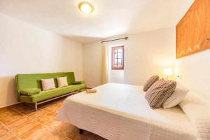 1 dormitorio con 1 cama y 1 sofá verde en Finca Cas Contador Mallorca en Algaida