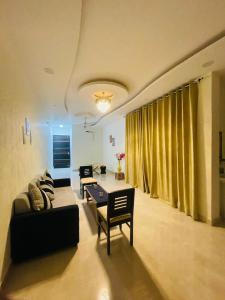 een woonkamer met een bank en een tafel bij Atulyam Stays Sushant Golf City in Lucknow