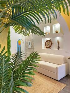 La suite Carthagène des Indes - centre ville , spa & terrasse privée في بيتون: غرفة معيشة بها أريكة بيضاء و نخلة